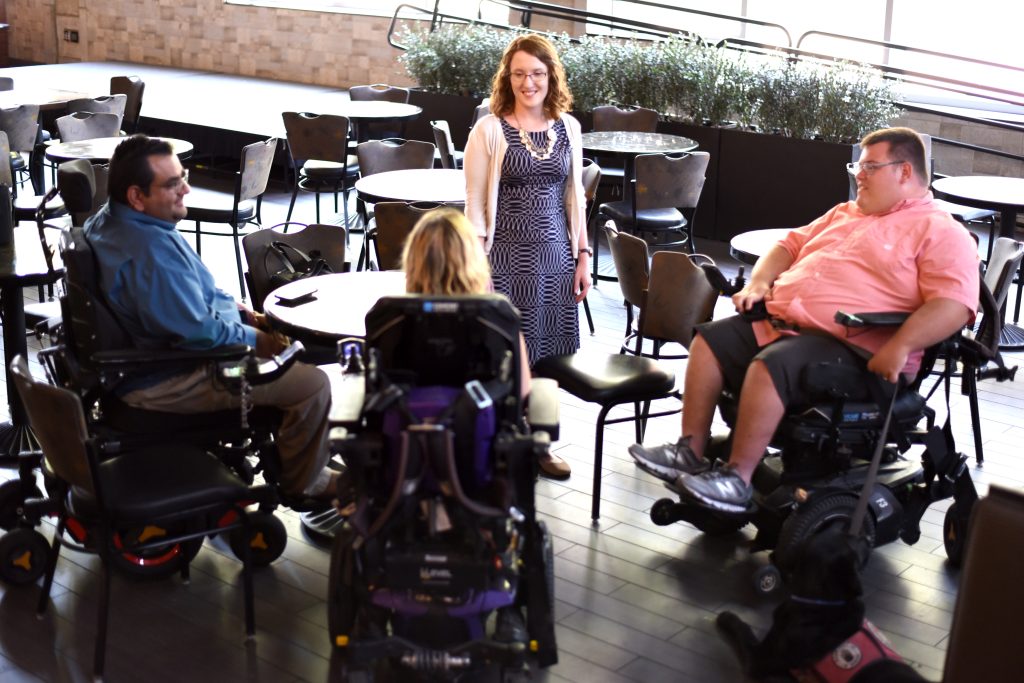 Photo of four people having a conversation, three of which are wheelchair users.