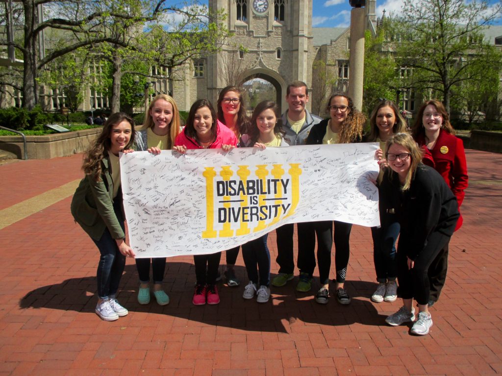 Photo of students holding a "disability is diversity banner"