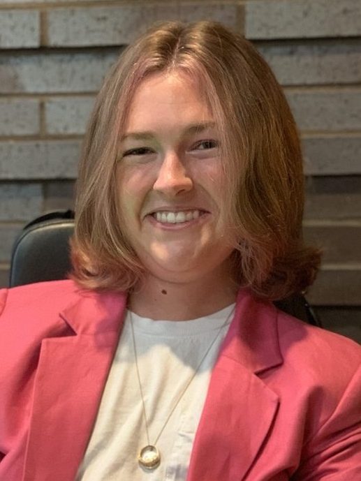 Ellie, a smiling young woman wearing a pink blazer.